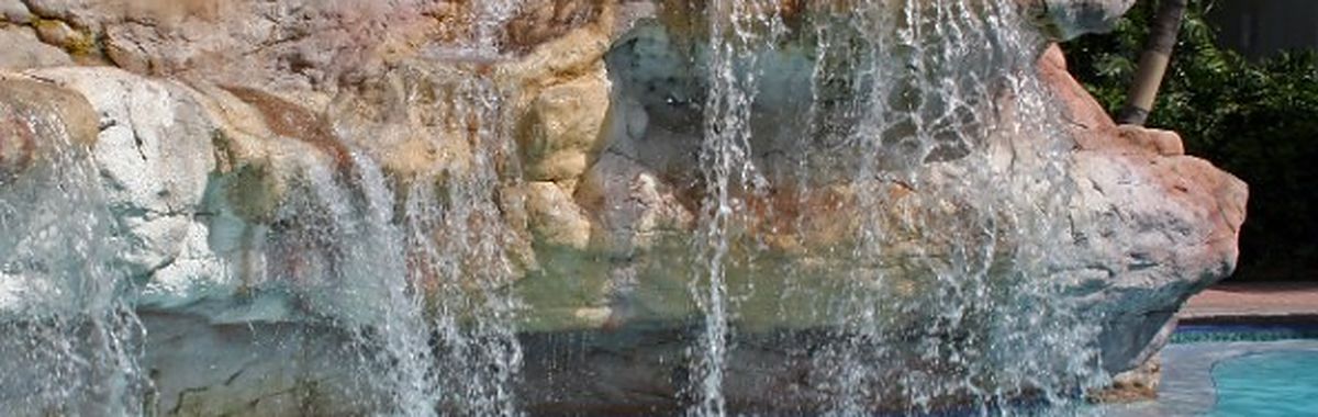 Cascada de roca natural sobre una piscina con zona de hidromasaje