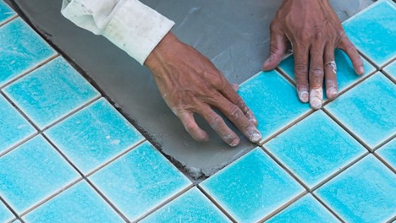 Operario colocando gresite azul en el vaso de una piscina