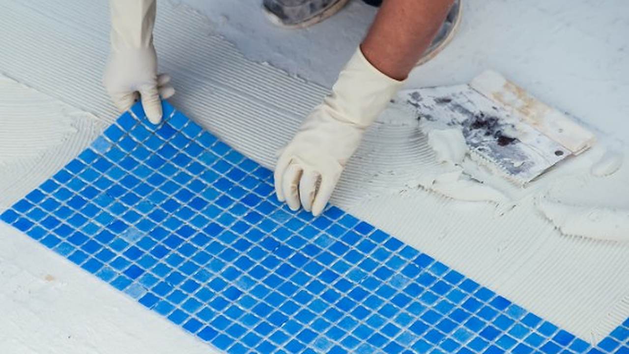 Operario colocando revestimiento cerámico en mosaico en una zona húmeda