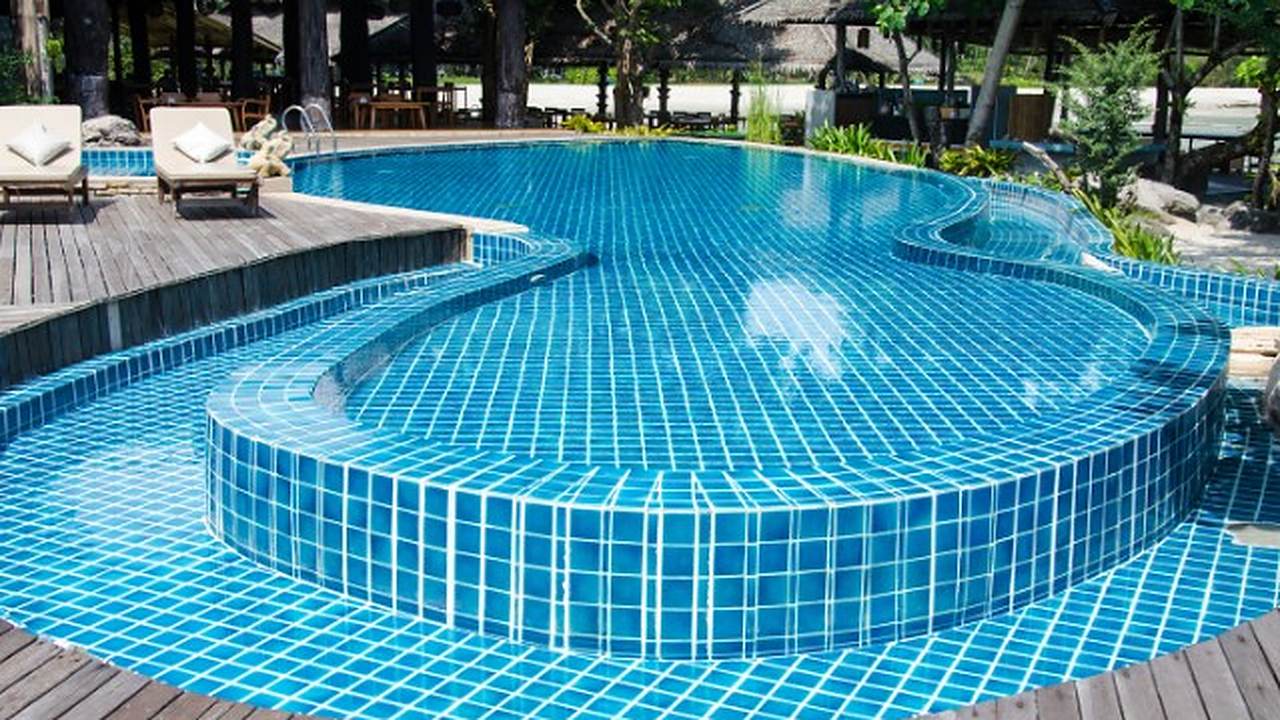 Piscina de formas libres con gresite azul e isla central en un complejo de la Costa del Sol