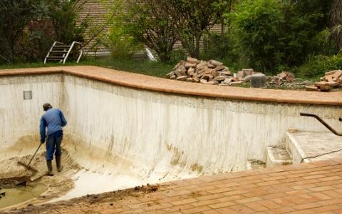 Operario saneando el vaso vacío de una piscina antes de rehabilitarla