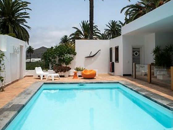 Piscina de una villa blanca con palmeras tras su mantenimiento en Marbella