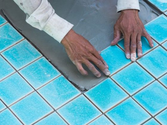 Técnico colocando gresite nuevo en el vaso de una piscina en la Costa del Sol